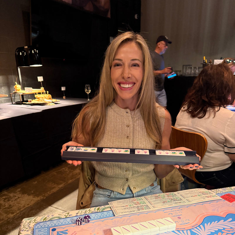 Woman holding a domino set with a colorful board game in front of her