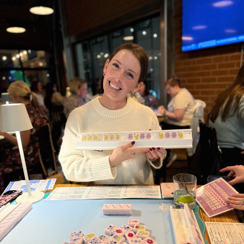 Woman holding a tray with tiles at a mahjong game in a casual setting