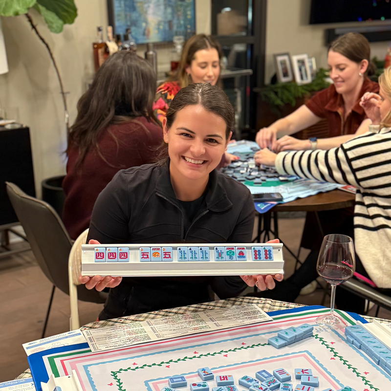 happy mahjong player holding mahjong rack of tiles